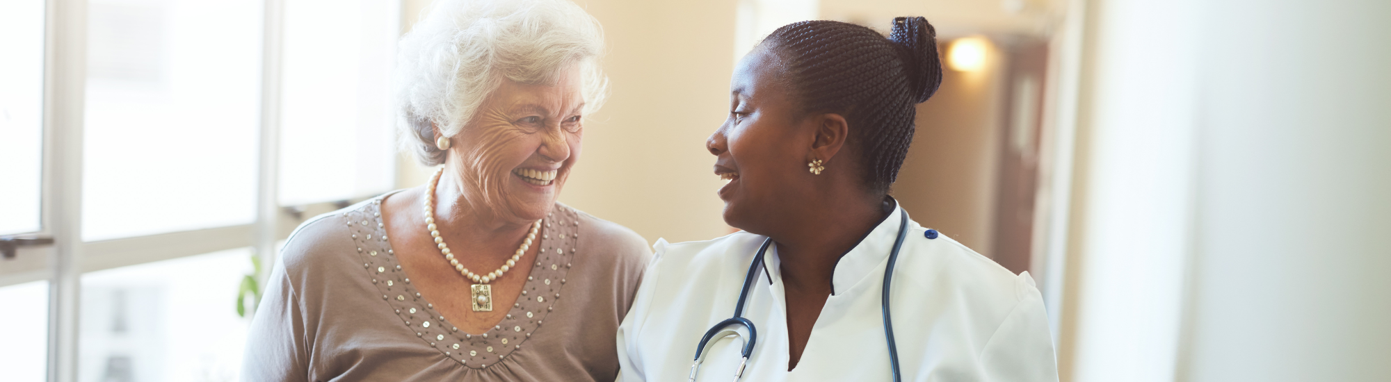 A nurse and an elderly lady laughing together.