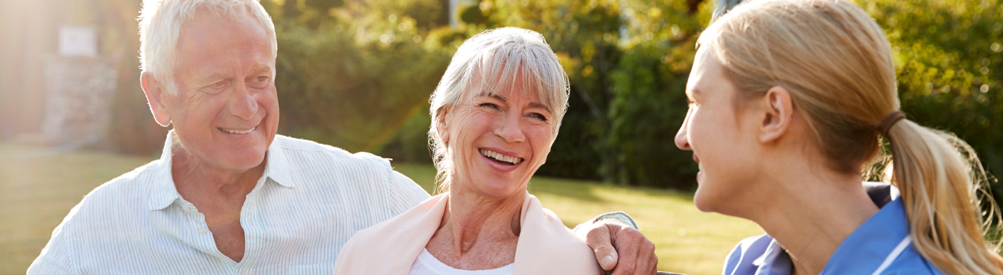 An elderly couple laughing with a nurse. 