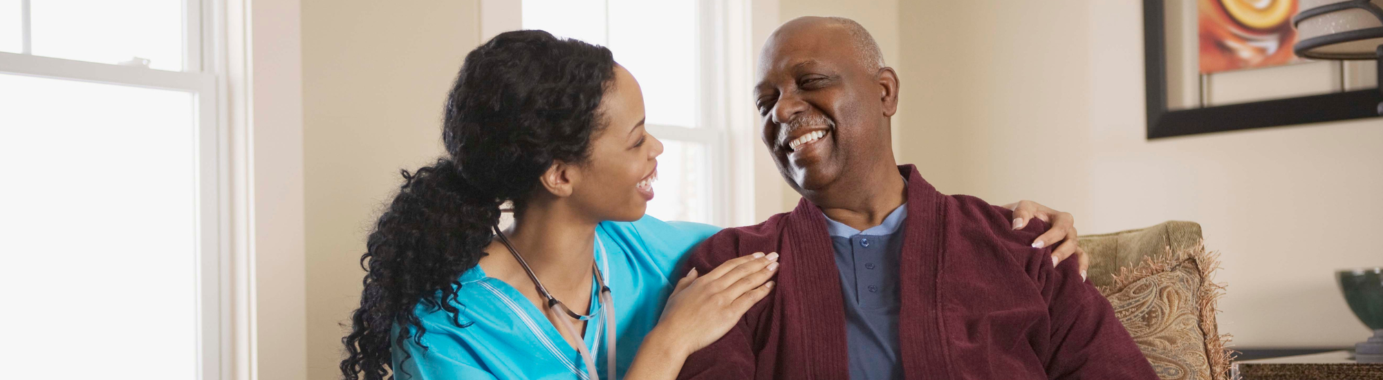 A nurse and an elderly man are laughing together.